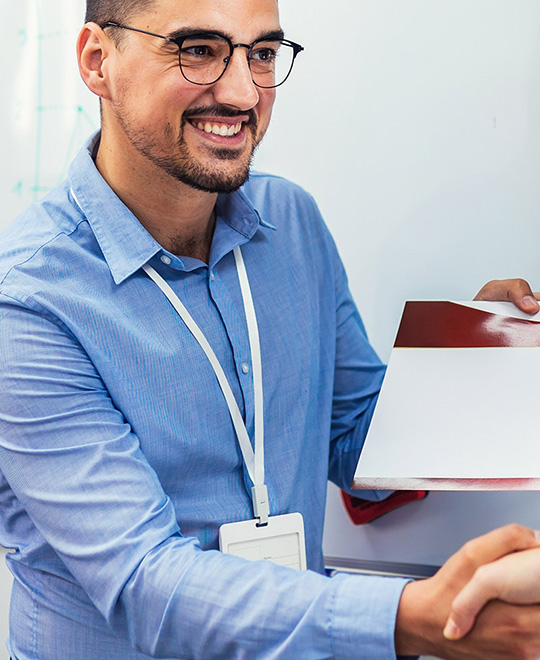 Mann in blauem Hemd verleiht Zertifikat an Sch&uuml;ler