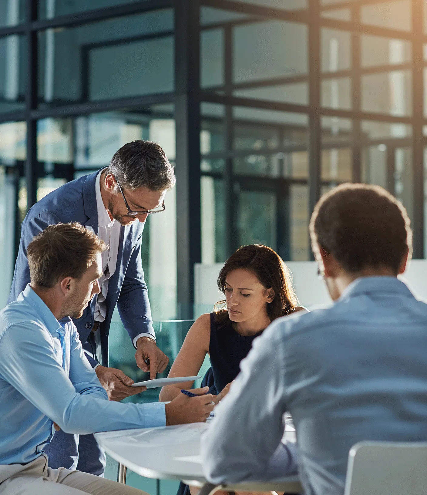 Vier Menschen sitzen um einen Tisch und besprechen etwas und schauen dabei auf ein Tablet